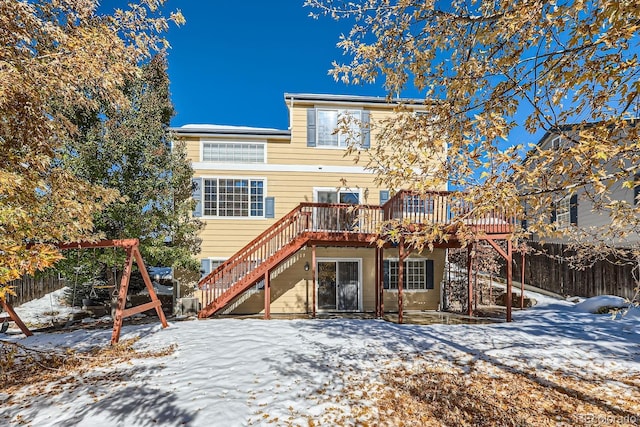 snow covered back of property with a wooden deck