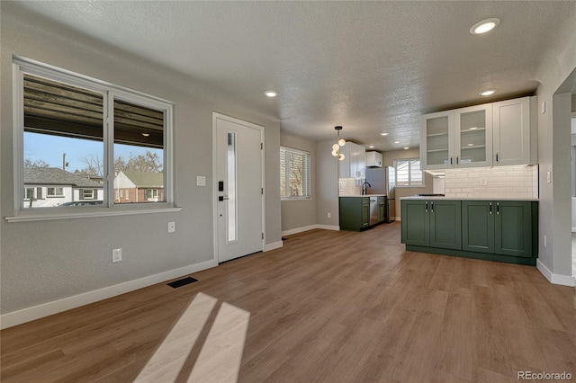 interior space with decorative backsplash, light wood-style floors, green cabinets, and white cabinets