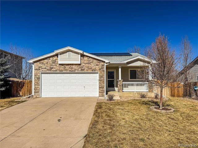 view of front of house with driveway, covered porch, fence, roof mounted solar panels, and a front lawn