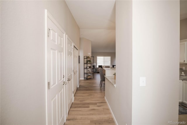 hall with light wood-style floors and baseboards