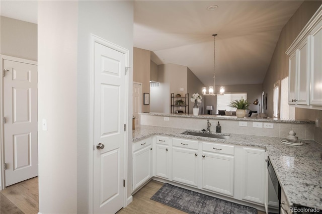 kitchen featuring white cabinets, lofted ceiling, an inviting chandelier, light wood-style floors, and a sink