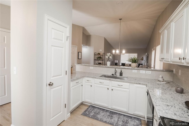 kitchen with a chandelier, lofted ceiling, light stone counters, a sink, and white cabinetry