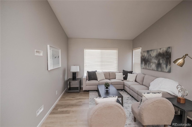 living room featuring lofted ceiling, light wood-style flooring, and baseboards