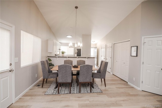 dining room featuring high vaulted ceiling, baseboards, a notable chandelier, and light wood finished floors