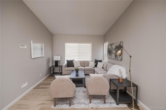 living room with light wood-type flooring, baseboards, and vaulted ceiling