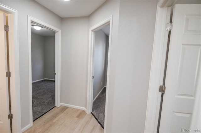 corridor featuring light wood-type flooring and baseboards