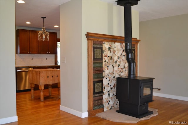 interior space featuring backsplash, a wood stove, dishwasher, and wood-type flooring