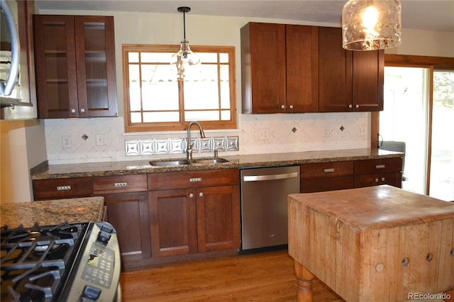 kitchen with light wood-type flooring, light stone countertops, sink, and appliances with stainless steel finishes