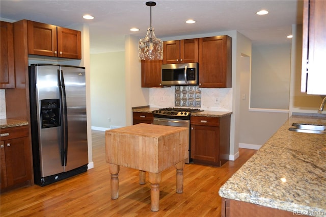 kitchen featuring light stone countertops, sink, a kitchen island, and appliances with stainless steel finishes