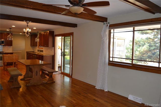 dining area with beamed ceiling, plenty of natural light, dark hardwood / wood-style floors, and ceiling fan with notable chandelier