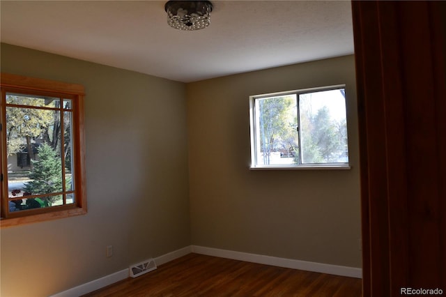 spare room featuring dark hardwood / wood-style floors and a healthy amount of sunlight