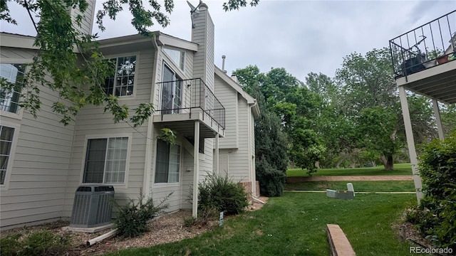 13854 E Lehigh Ave Unit D, Aurora, CO 80014 - view of side of property featuring central AC, a balcony, a lawn, and a chimney