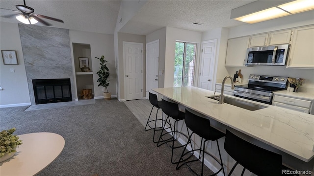 13854 E Lehigh Ave Unit D, Aurora, CO 80014 - kitchen featuring stainless steel appliances, carpet flooring, a textured ceiling, a sink, and baseboards