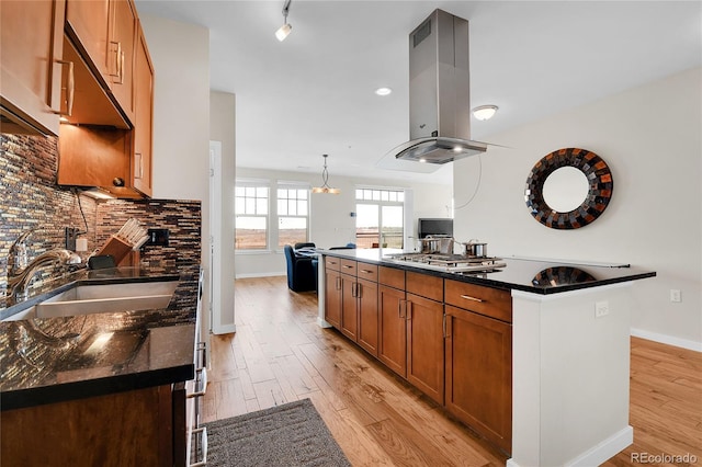 13598 Via Varra Unit 301, Broomfield, CO 80020 - kitchen featuring island exhaust hood, light wood-type flooring, brown cabinetry, a center island with sink, and stainless steel gas cooktop