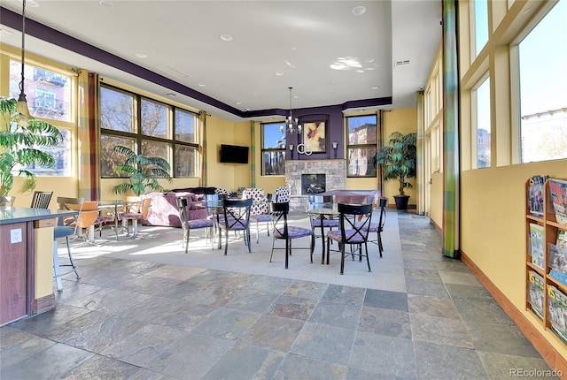 13598 Via Varra Unit 301, Broomfield, CO 80020 - dining space featuring stone tile flooring, a stone fireplace, and a chandelier