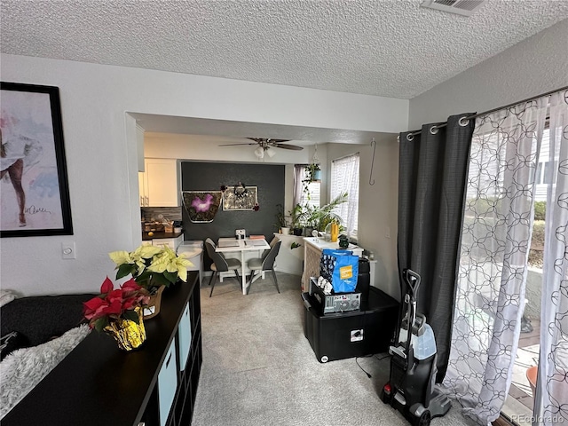 carpeted living room featuring ceiling fan and a textured ceiling