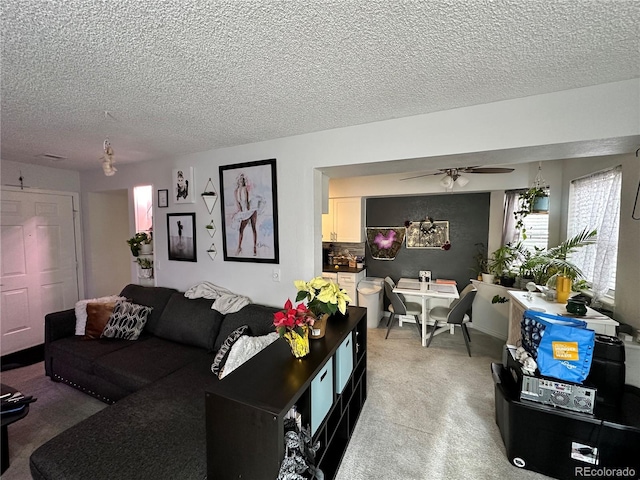 living room with light carpet, a textured ceiling, and ceiling fan