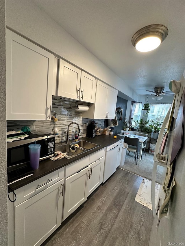 kitchen featuring white dishwasher, dark hardwood / wood-style flooring, white cabinets, and tasteful backsplash