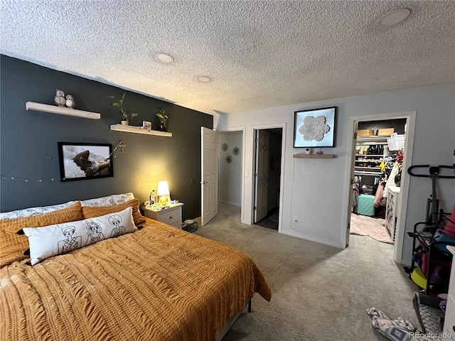 carpeted bedroom with a textured ceiling, a spacious closet, and a closet