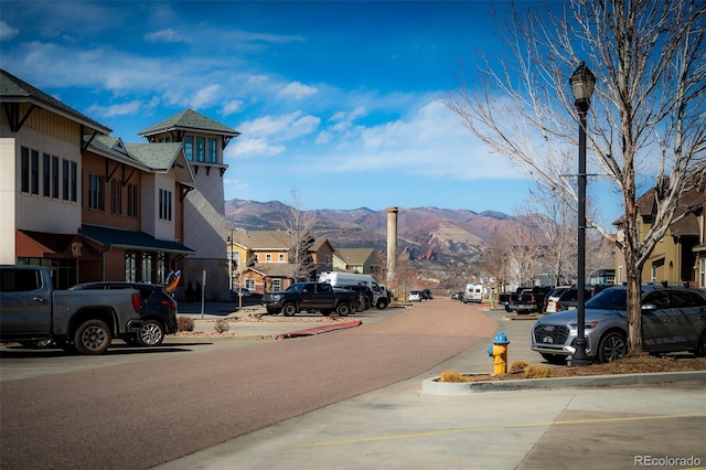 view of road featuring street lighting, curbs, a mountain view, and a residential view