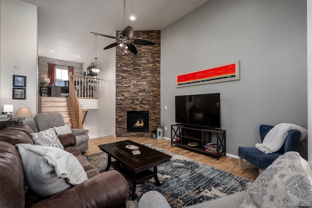 living area with baseboards, ceiling fan, wood finished floors, stairs, and a fireplace