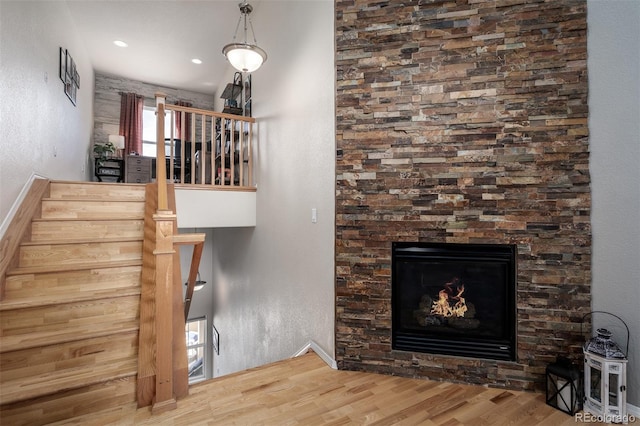 stairway with a glass covered fireplace and wood finished floors