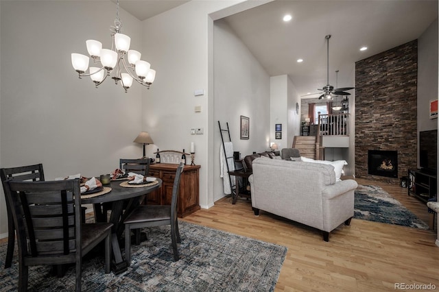 dining space featuring recessed lighting, a fireplace, light wood-style flooring, and ceiling fan with notable chandelier