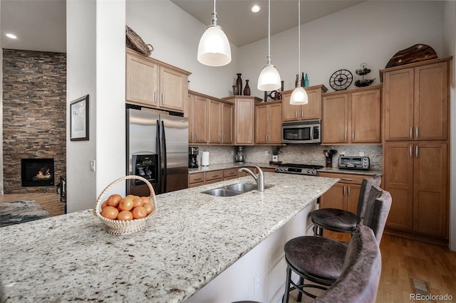 kitchen with a kitchen bar, decorative backsplash, stainless steel appliances, and a sink