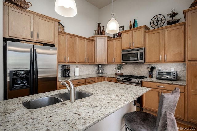 kitchen with a breakfast bar, a sink, hanging light fixtures, appliances with stainless steel finishes, and backsplash