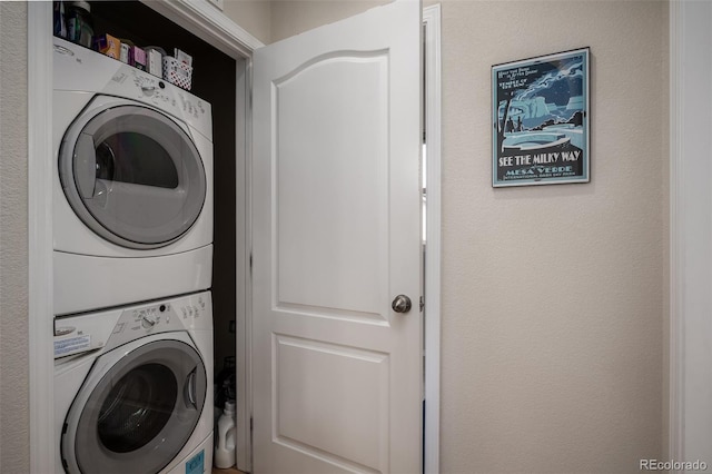 laundry area with laundry area, a textured wall, and stacked washing maching and dryer