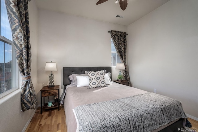 bedroom featuring light wood-type flooring, baseboards, visible vents, and ceiling fan