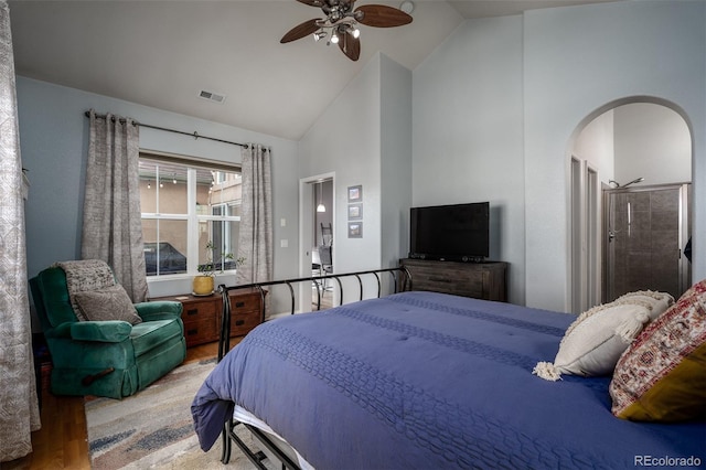 bedroom with arched walkways, visible vents, a ceiling fan, wood finished floors, and high vaulted ceiling