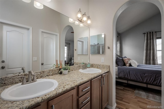 bathroom with double vanity, wood finished floors, ensuite bath, and a sink