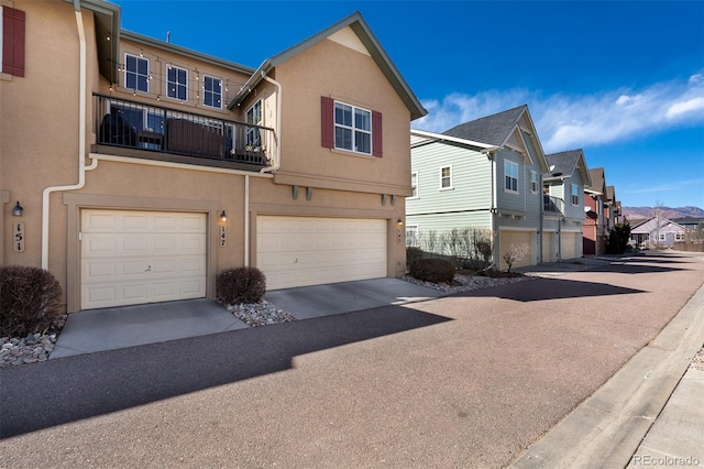 view of property featuring a garage, a residential view, driveway, and stucco siding