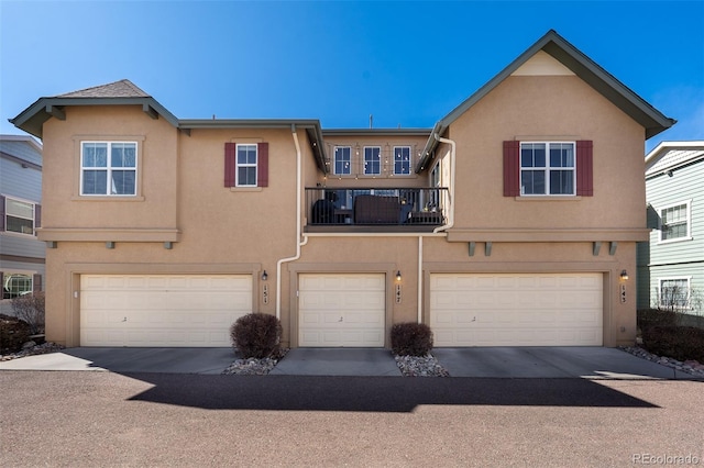 multi unit property featuring a balcony, an attached garage, and stucco siding