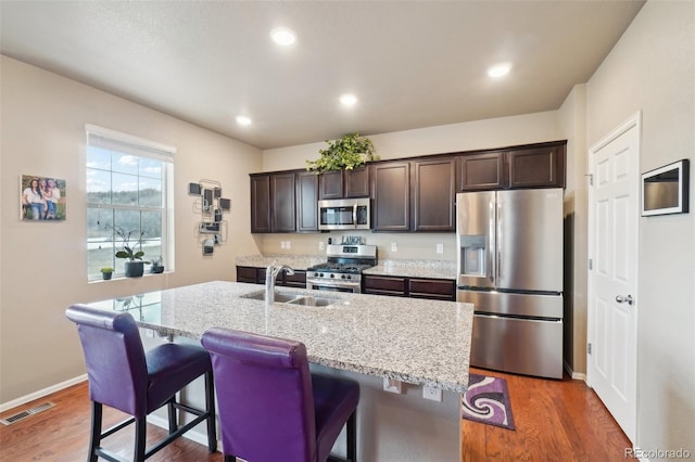 kitchen featuring visible vents, a sink, wood finished floors, appliances with stainless steel finishes, and dark brown cabinets