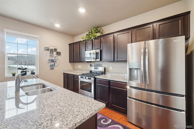 kitchen featuring light wood-style flooring, recessed lighting, a sink, stainless steel appliances, and dark brown cabinetry