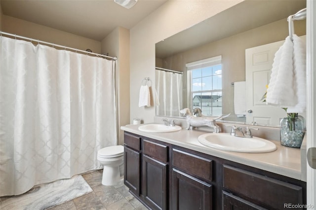 bathroom with double vanity, toilet, and a sink