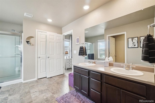 bathroom with a sink, visible vents, a stall shower, and double vanity