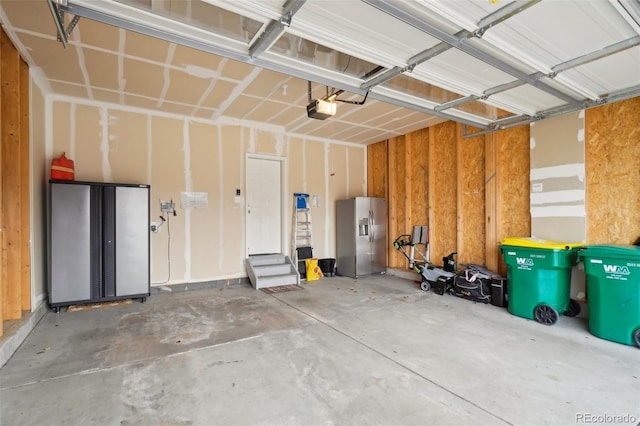 garage featuring stainless steel fridge and a garage door opener