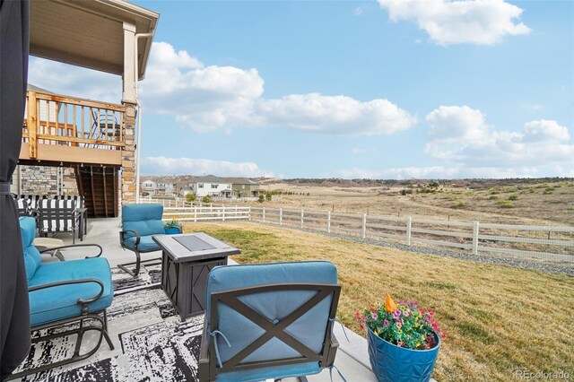 view of patio with stairway, a rural view, an outdoor living space with a fire pit, and fence