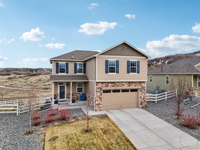 view of front of property with fence, roof with shingles, an attached garage, concrete driveway, and stone siding