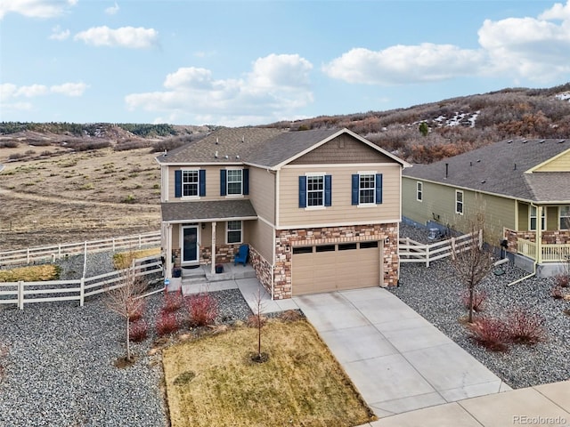 view of front of home with concrete driveway, a garage, fence, and stone siding