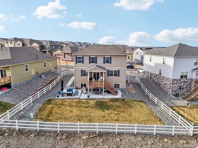 back of property with a fenced backyard, a residential view, and a patio