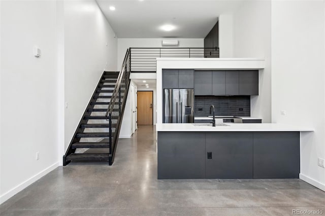 kitchen with kitchen peninsula, stainless steel refrigerator with ice dispenser, gray cabinets, and sink