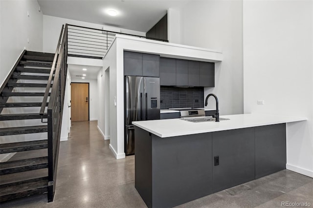 kitchen with kitchen peninsula, stainless steel fridge with ice dispenser, tasteful backsplash, and sink