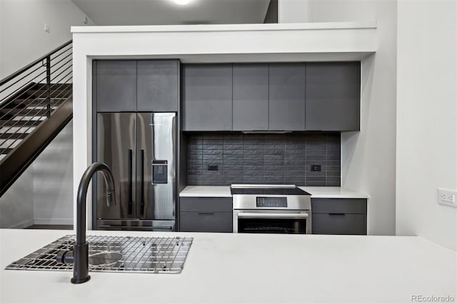 kitchen with gray cabinetry, decorative backsplash, sink, and stainless steel appliances