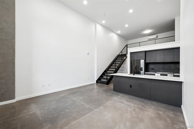 unfurnished living room with sink, a high ceiling, and concrete floors