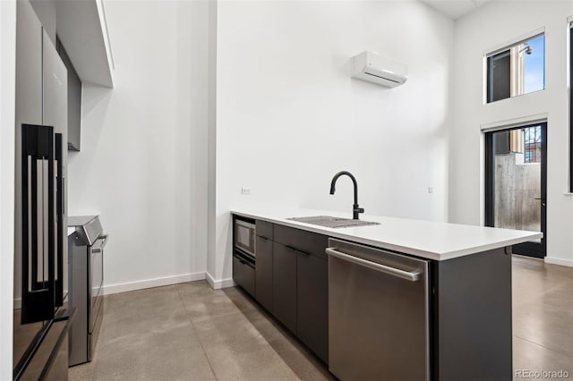 kitchen featuring kitchen peninsula, appliances with stainless steel finishes, dark brown cabinetry, a wall mounted AC, and sink