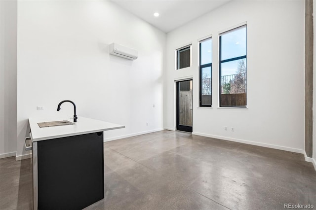 interior space with a wall mounted air conditioner, concrete floors, kitchen peninsula, and sink